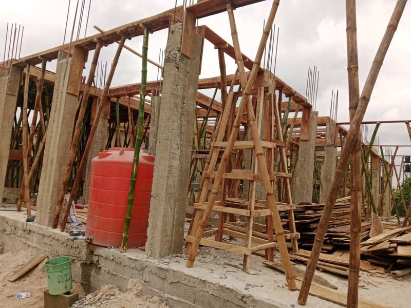 Concrete columns and timber formwork supported by bamboo props on a building site