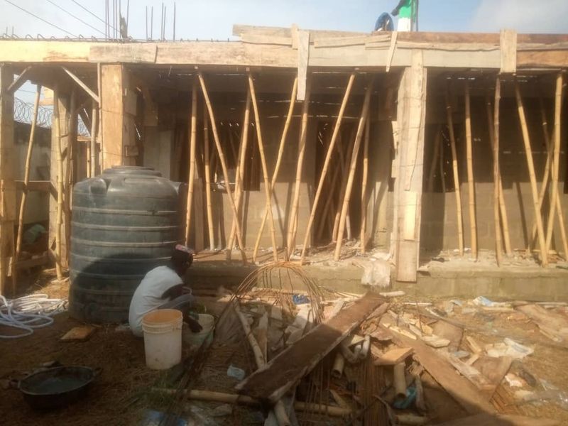 Worker beside a water tank under a propped slab